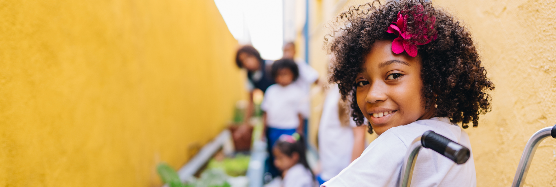 Image d’une jeune fille souriante en fauteuil roulant avec une  fleur rose dans les cheveux