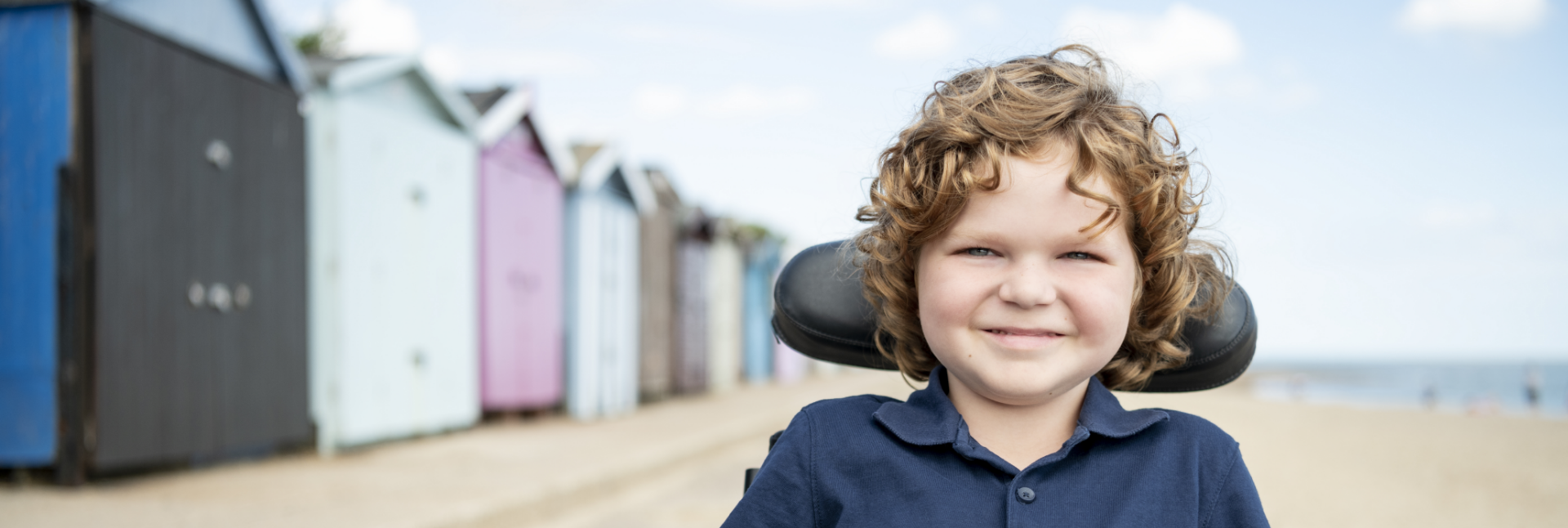 Image d’un jeune garçon souriant en fauteuil roulant sur une plage